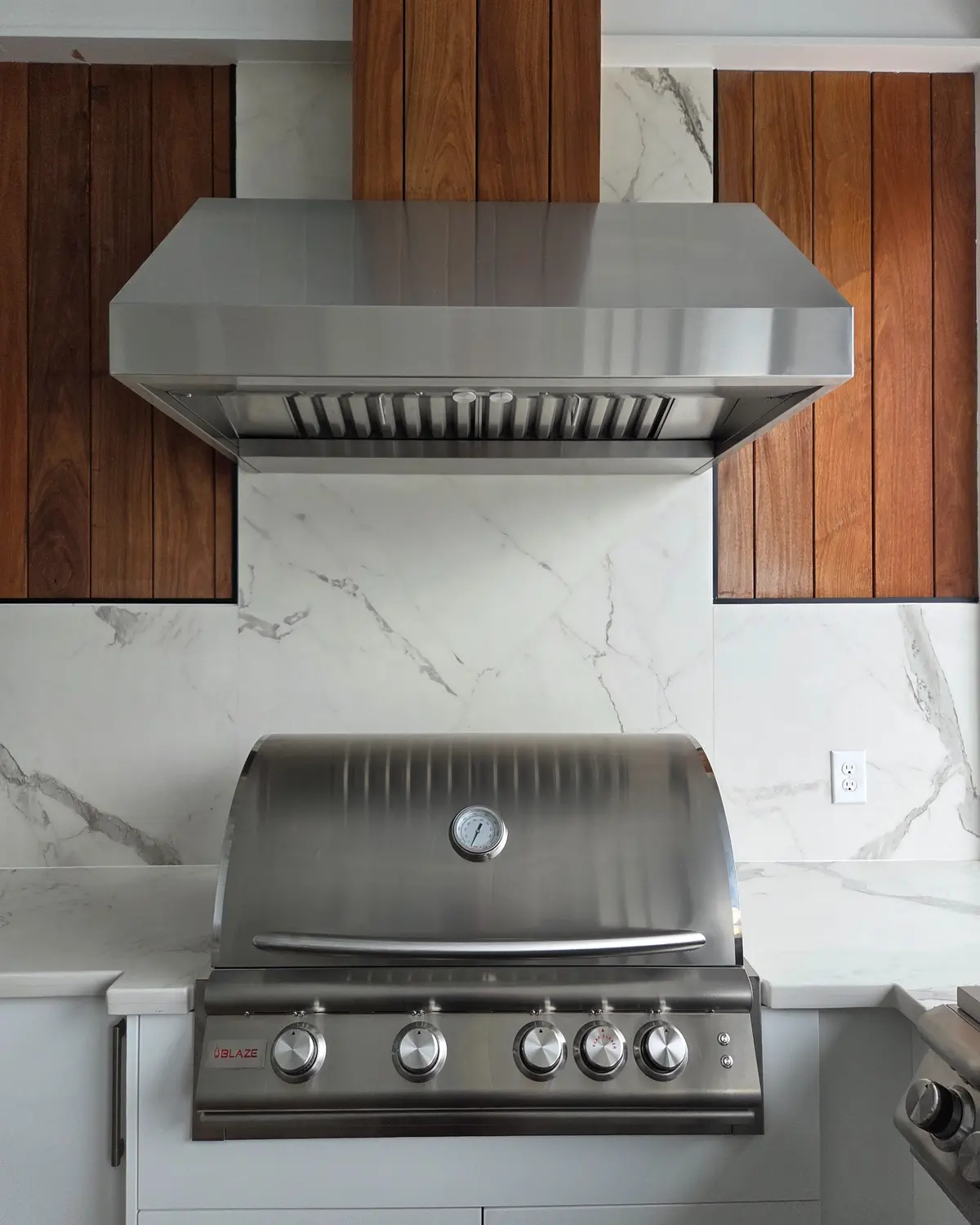 Clean built-in Blaze grill and vent hood in a custom outdoor kitchen