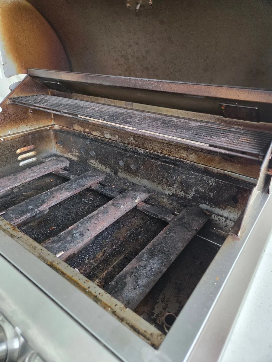 Blaze five-burner with the grates out, before: carbon on the firebox and rust on the flame tamers
